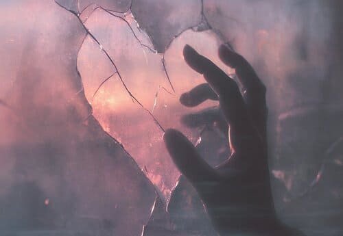 Hand an Herz aus Fensterglas gesprungen